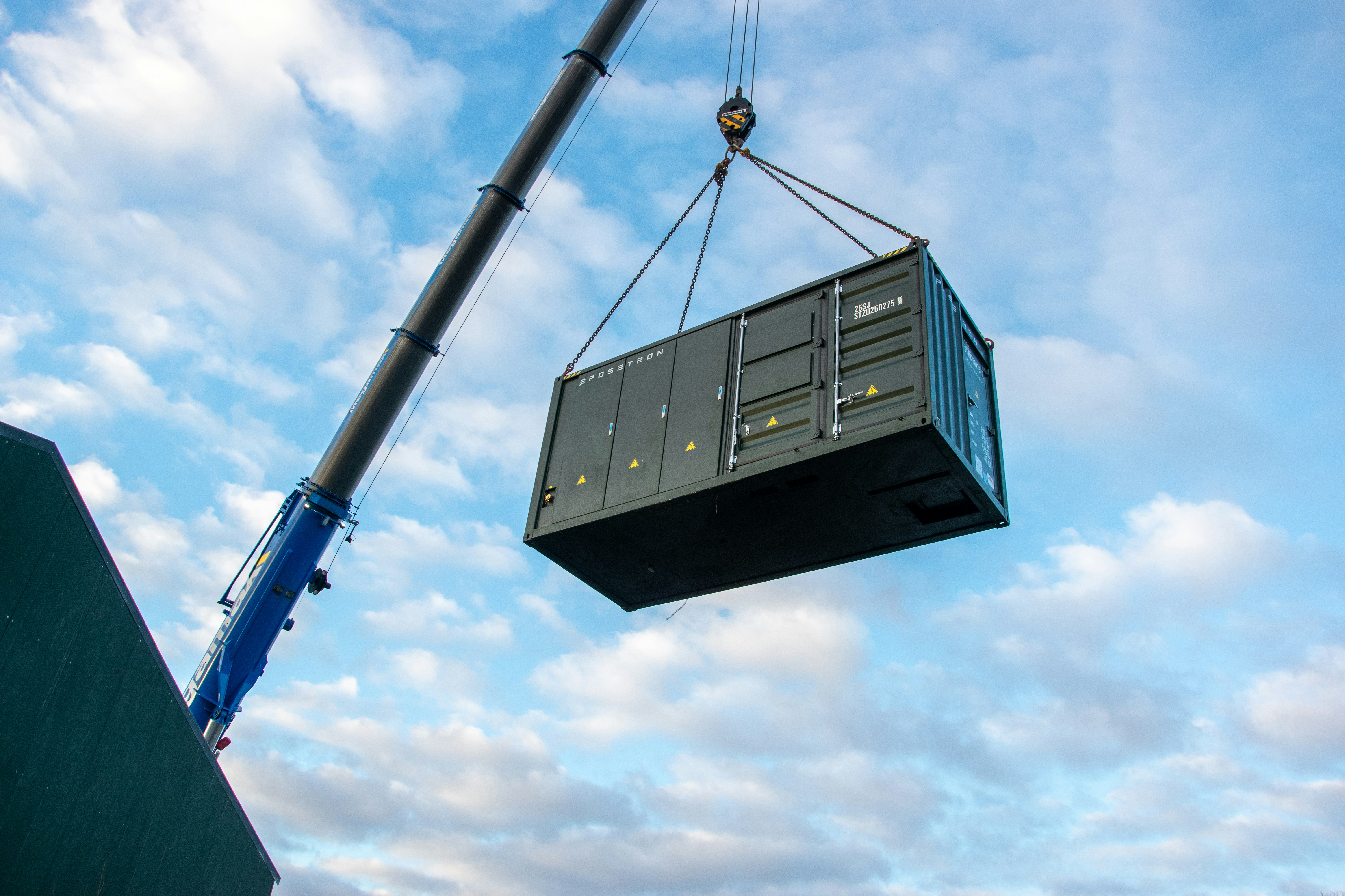 Containerized battery energy storage system (BESS) unit being lifted by crane